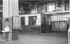 Machine shop. Tool room. Note drinking water fountain with salt tablet dispenser above. Time card (out) rack. Time clock hung behind fountain